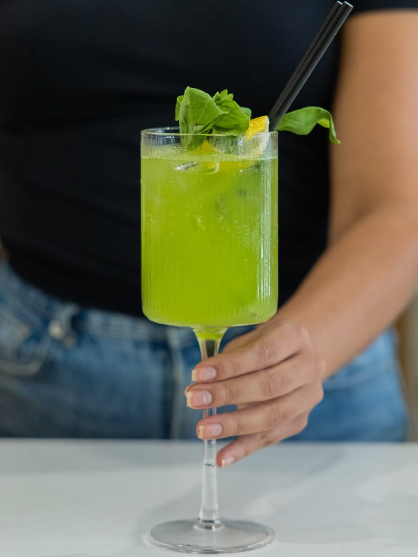 Bright green basil smash cocktail garnished with fresh basil and lemon